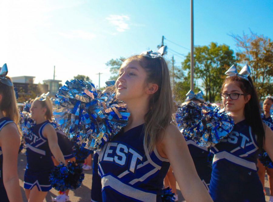 Sophomore Charliegh Thomas and the rest of the cheerleaders march with the dance team, band, and other representatives of Olathe West in the Old Settlers Day Parade.