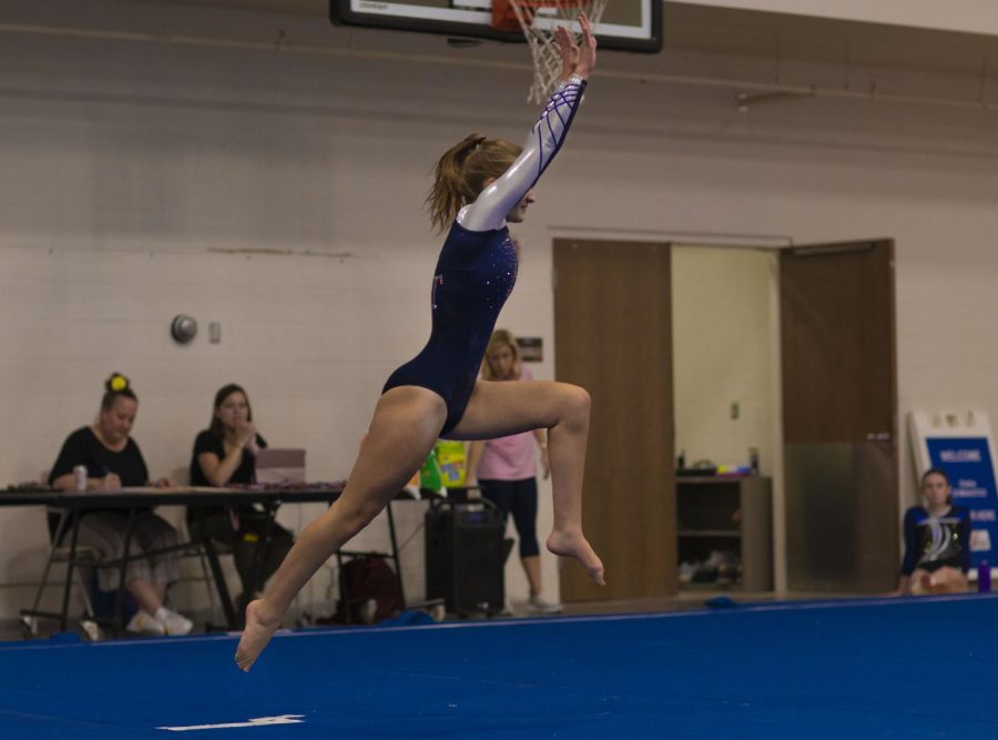 Junior Ava Huntoon springs into the air as the judges, announcers and other team mates watch from the sidelines.
