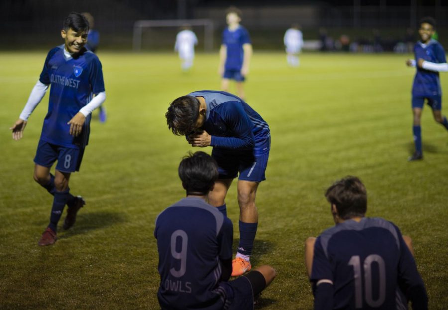 Senior Efrain Balleza looks on as senior Wesley Sirivongxay bends down in a praying position after scoring a goal. Sirivongxay is nicknamed Buddha from teammates and fans.
