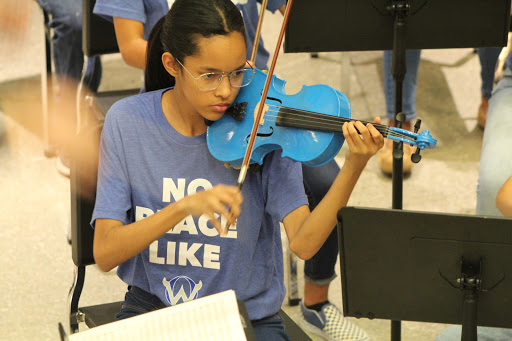 Freshman Destiny Anthony performs with the Freshman Orchestra, displaying her blue instrument during the Night in Italy concert. The night began with middle school performances from Mission Trail and Oregon Trail.