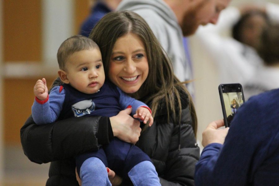 Head cross country coach Kelsey Carbajo takes a picture with wrestling assistant coach Lucas Vincent’s son, Magnus, during the meet. Carbajo had just come from the district office where she was honored as Kansas Cross Country Coach of the Year.
