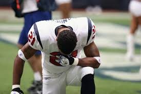 Patriots player kneels before game during national anthem among other teammates. 
