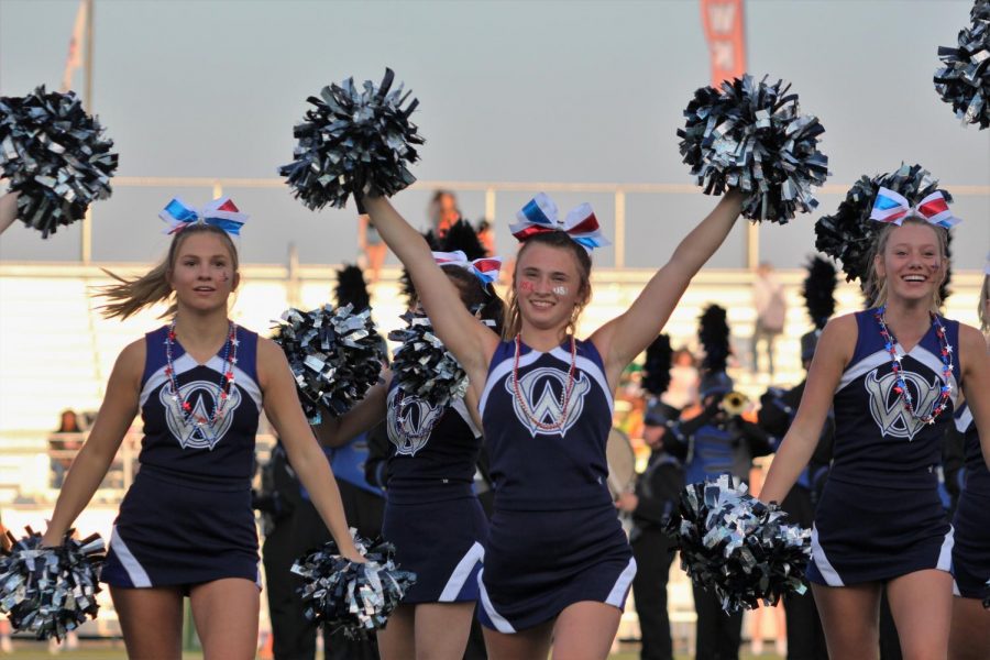 Senior Ava Schreck leads the cheerleaders as the football team runs onto the field at the beginning of the game against Shawnee Mission Northwest on Sept. 9.
