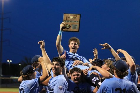 Sophomore Cameron Carter holds the trophy and celebrates with the team after winning the Regional Championship game against Olathe South. Owls won in extra innings with a final score of 2-1.