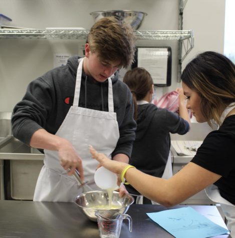 Junior Cater Forbes whisks pancake mix while sophomore Gianna Garcia-Campos pours in batter.