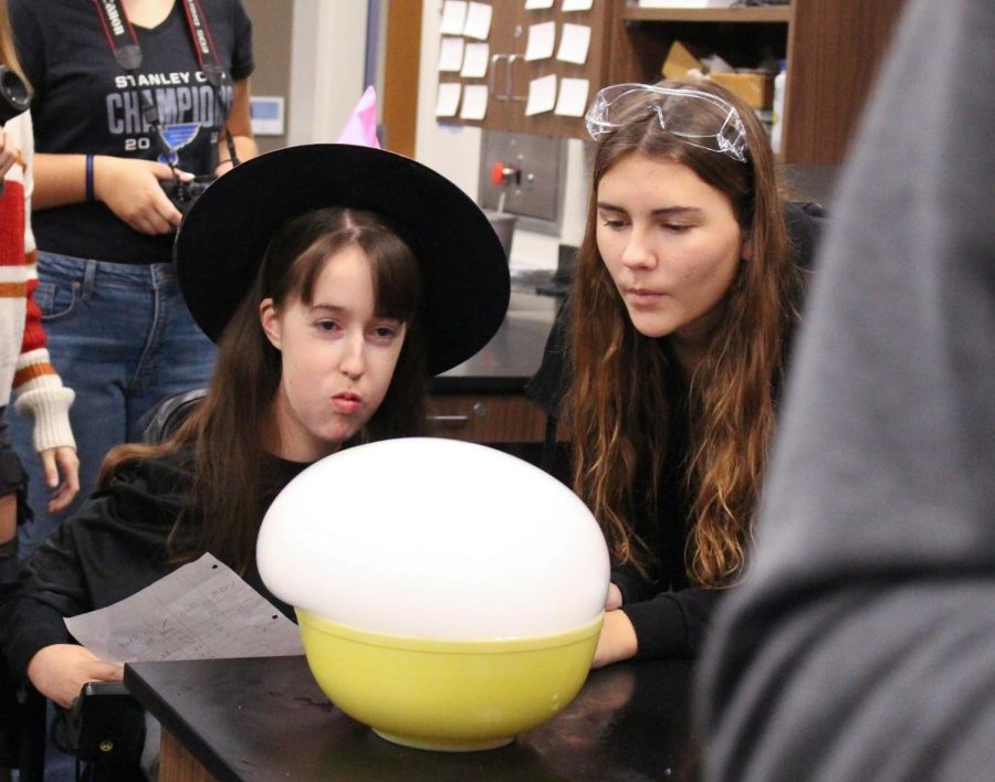 In Nikki Burnett’s Chem-o-Ween class on Oct. 31, Aubrey May and Ava Covault blow on a dry ice bubble experiment.
