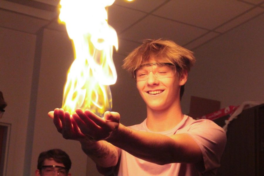 In Burnett’s Chem-o-ween presentation, Brayden Walker volunteers to hold fire in an experiment on Oct. 31.