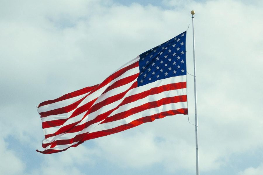 An american flag flaps in the wind on a flagpole. Original public domain image from Wikimedia Commons