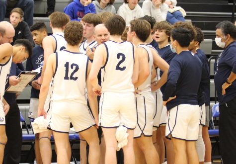 Coach Brad Ball, seen here in a huddle with the 2021-2022 varsity boys basketball team, is known for his compassionate coaching style.