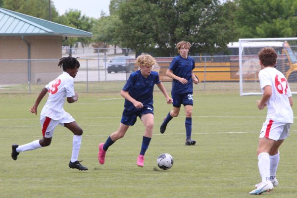 In the first soccer game of the season, freshman Drake Thomas on offense takes on a defender in the middle of the field as he looks for the next pass.