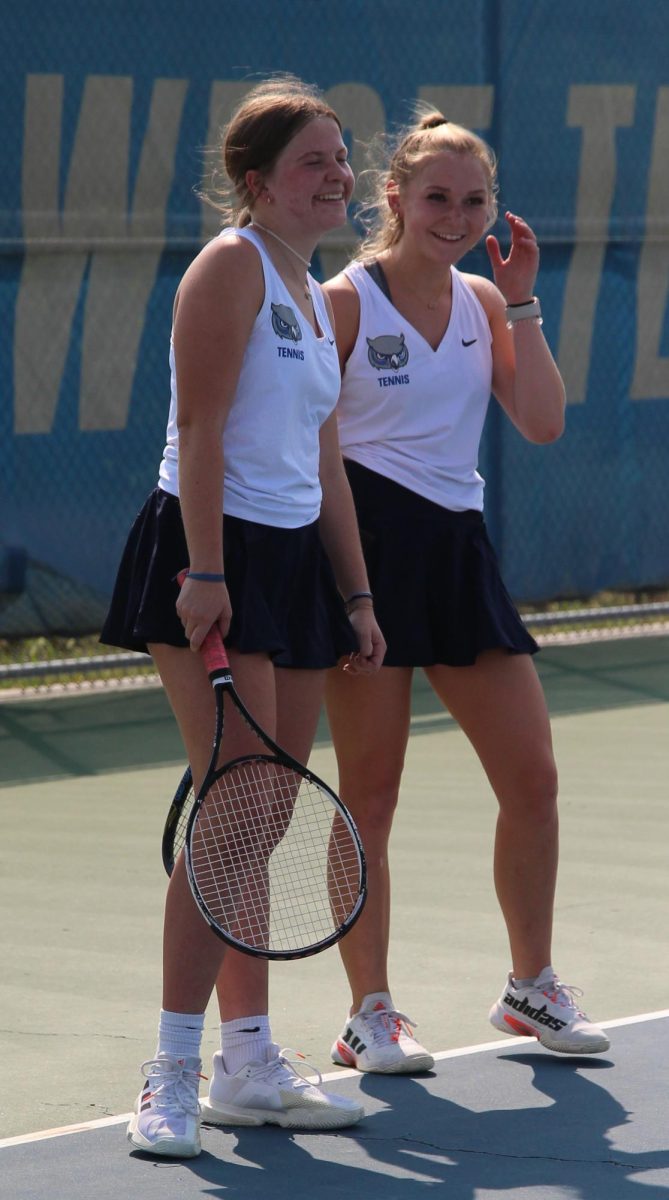 During the tennis first home meet, sophomores Tobi Clouse and Sophie Lewis laugh on the sidelines. 
