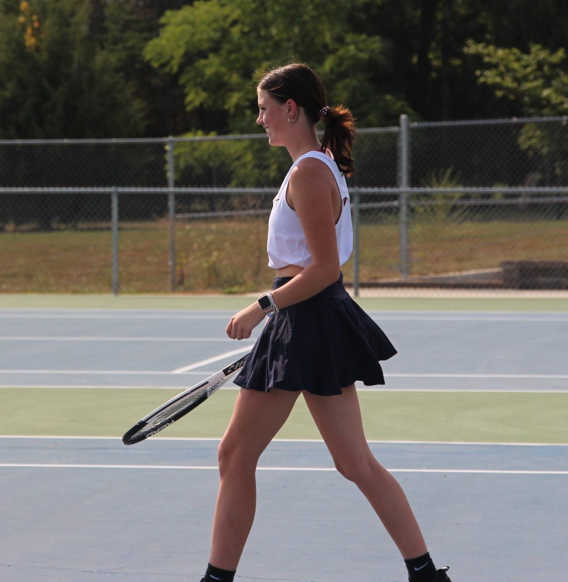 At the first home meet of the season against Shawnee Mission North, junior Lexi Barret walks towards the net. 
