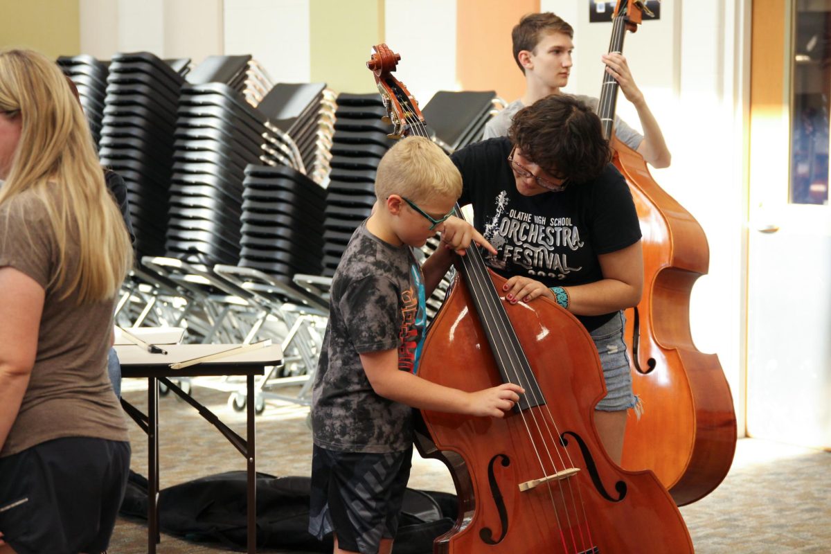 Senior Gizelle Romero helps a fifth grader hold and play the bass. 