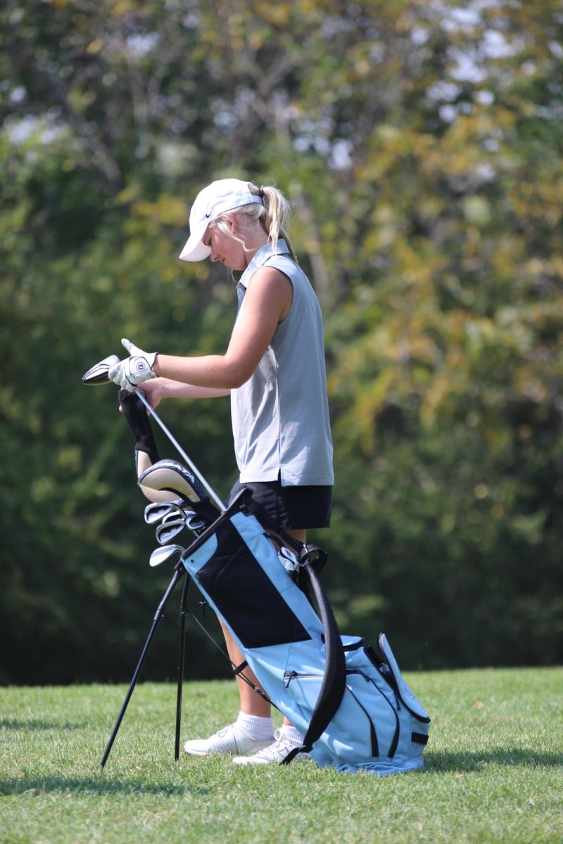 Varsity golfer, Lauryn Andresen, picks out which golf club she will use during the tournament against Shawnee Mission-North.
