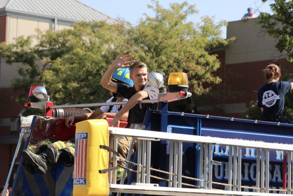 Senior Noah Jaye waves down from the firetruck at the crowd in the parade.