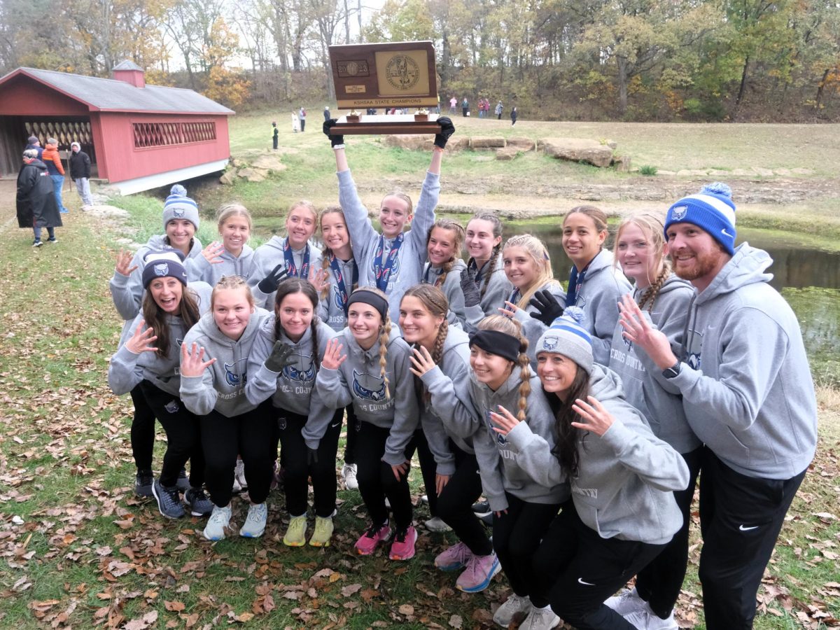 Varsity girls cross country poses with their hardware after winning their fourth state championship.