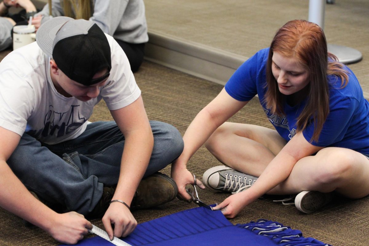 Senior Trevor Johnson and Topanga Wayman work on felt tie blankets in the library.