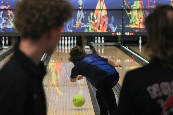 Senior Jakob Weber throws his bowling ball down the lane as students from other high schools watch.
