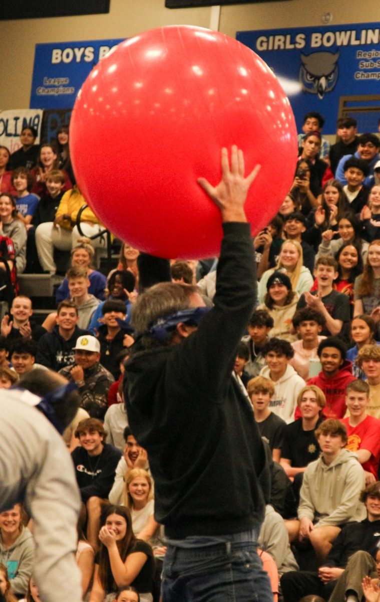 Math teacher Ryan Krzykowski holds the ball up as he wins the musical ball game at the winter pep assembly. Many teachers participated in this game where they find and sit on a ball when the music stops.