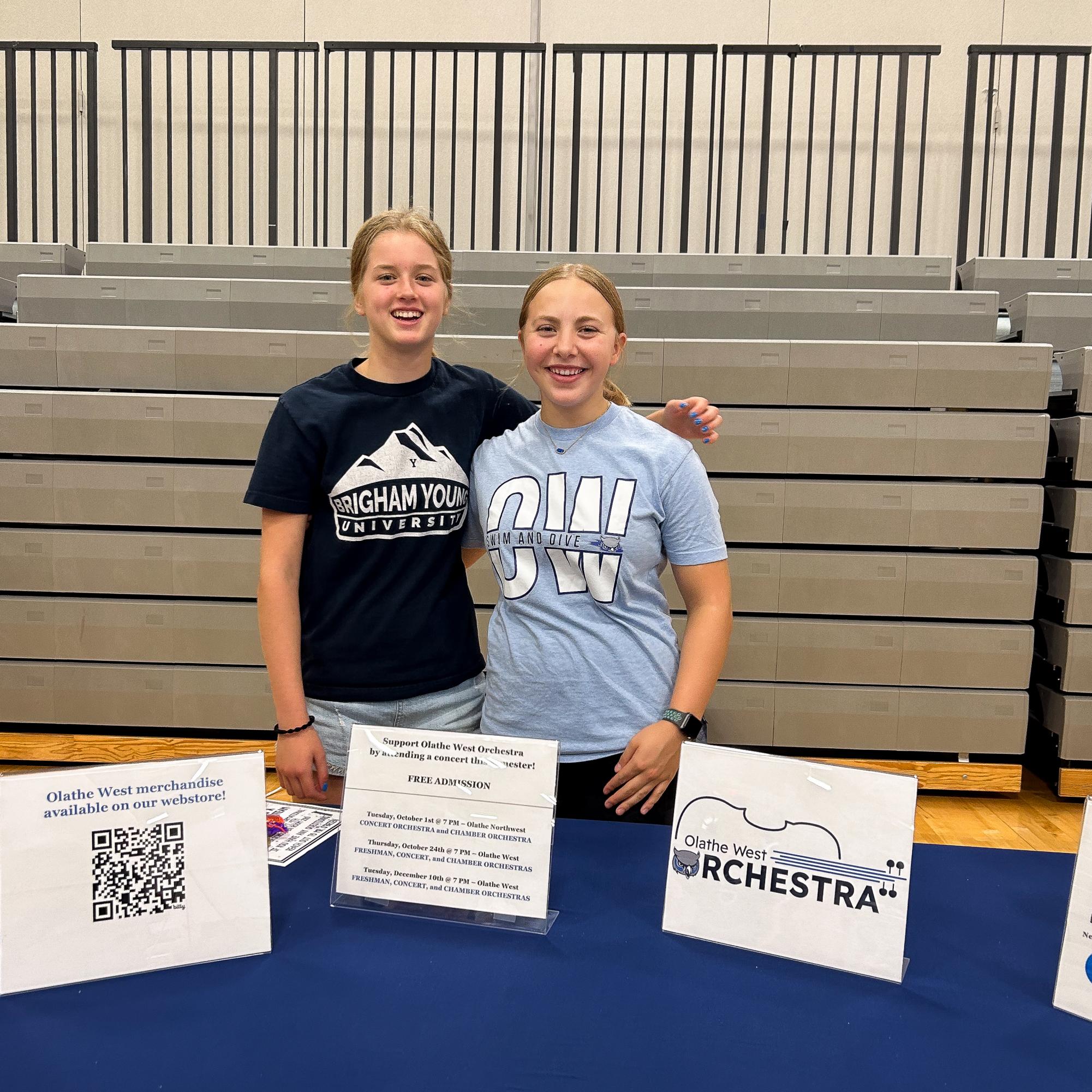 From left sophomore Ruth Duncan and junior Eliza Killough pose for a photo at the Orchestra table.