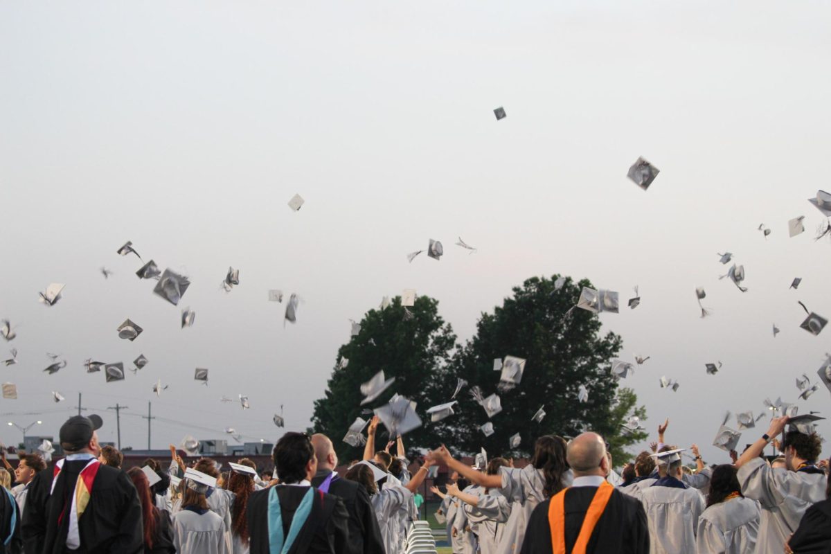 The graduates are seen throwing their caps in the air.