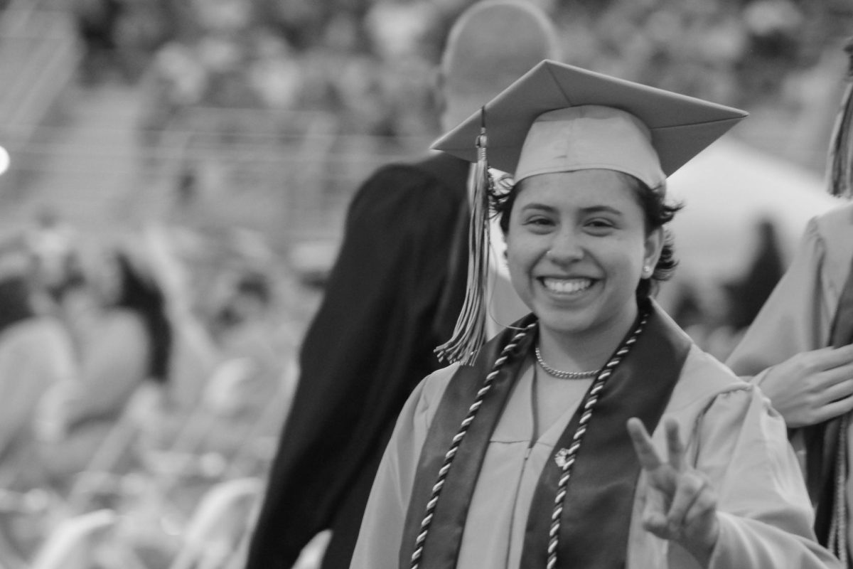 Senior Khiren Storme is smiling and doing a peace sign towards the camera.