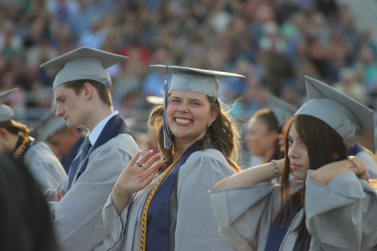 Senior Macy Orth is seen smiling and waving at the camera.