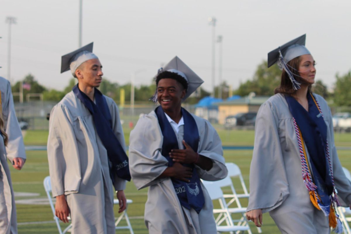 Senior David Walker walks to his seat while looking out into the audience.