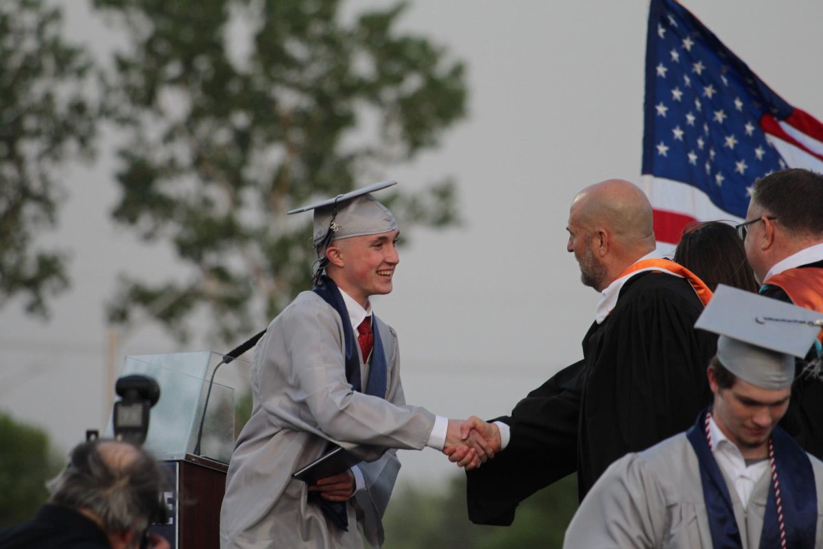 Senior Maxwell Archibald shakes hands with Principal Jay Novacek on stage.