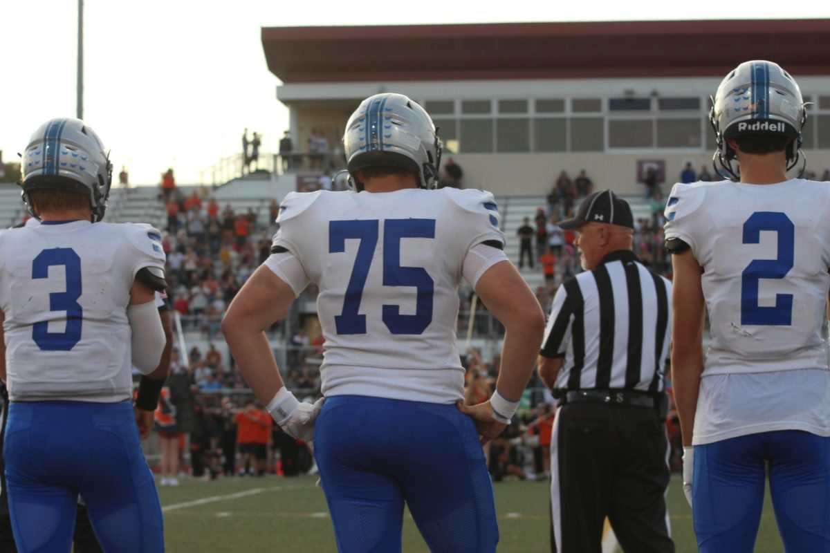 Senior Brody Hale (3), junior Mason Schneider (75) and senior Sam Krzykowski wait on the sideline against Shawnee Mission Northwest