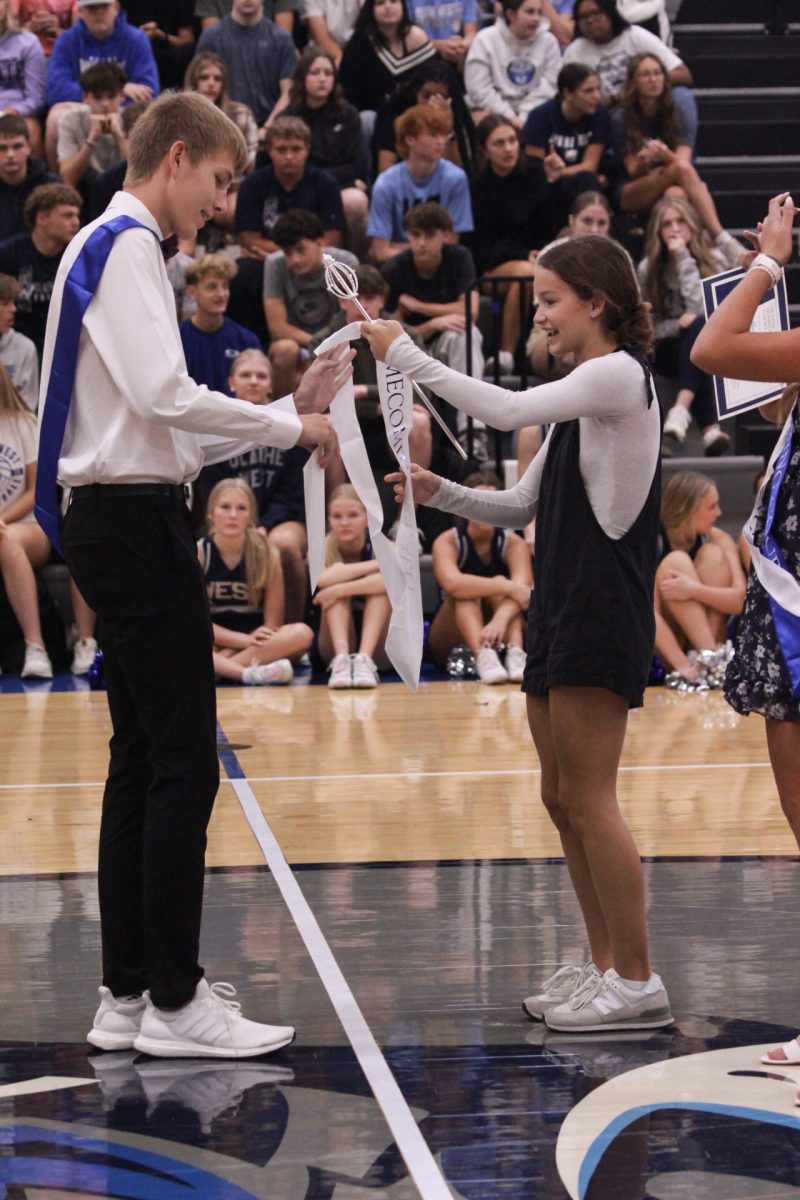 Molly Harding handing the sash and crown to Owen Boolinger