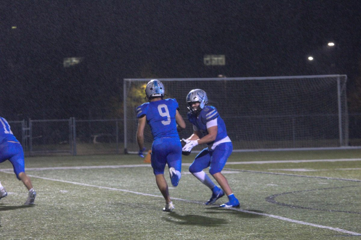 Junior Cash Warren (8) hands the ball off to senior Josh Foland (9) 