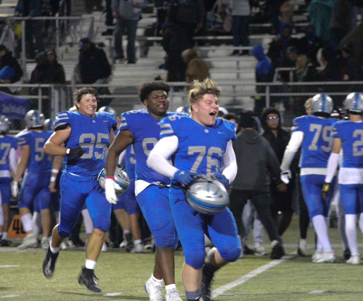 Junior Cooper Wiemers (76), as well as seniors Jalen Johnson (92) and Conner Tracy(95) run to join the Alma Mater line after a win vs Olathe Northwest