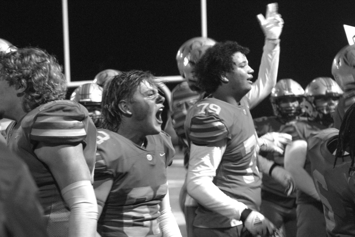 Junior Wyatt Benton yells towards the student section in celebration after beating Olathe Northwest