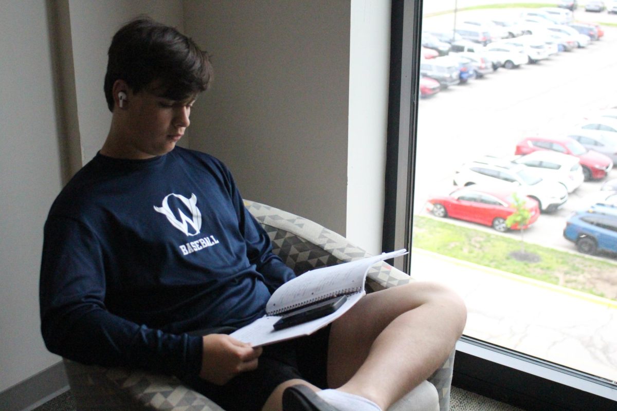Junior Caleb Robles looking at his phone which was hiding in a notebook.